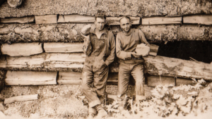 Two miners sitting in front of the cabin at Ape Canyon